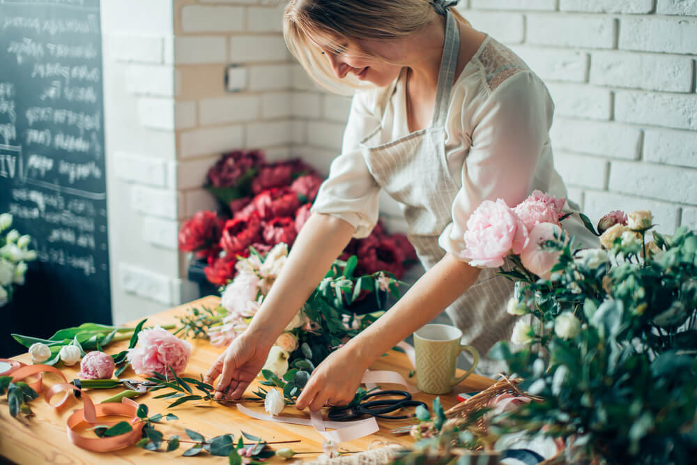Woman organizing flowers in small business flower shop