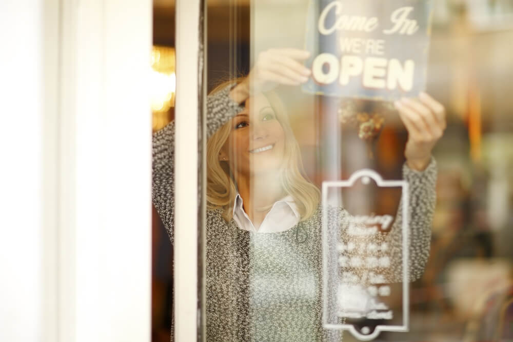 Small business owner putting up OPEN sign